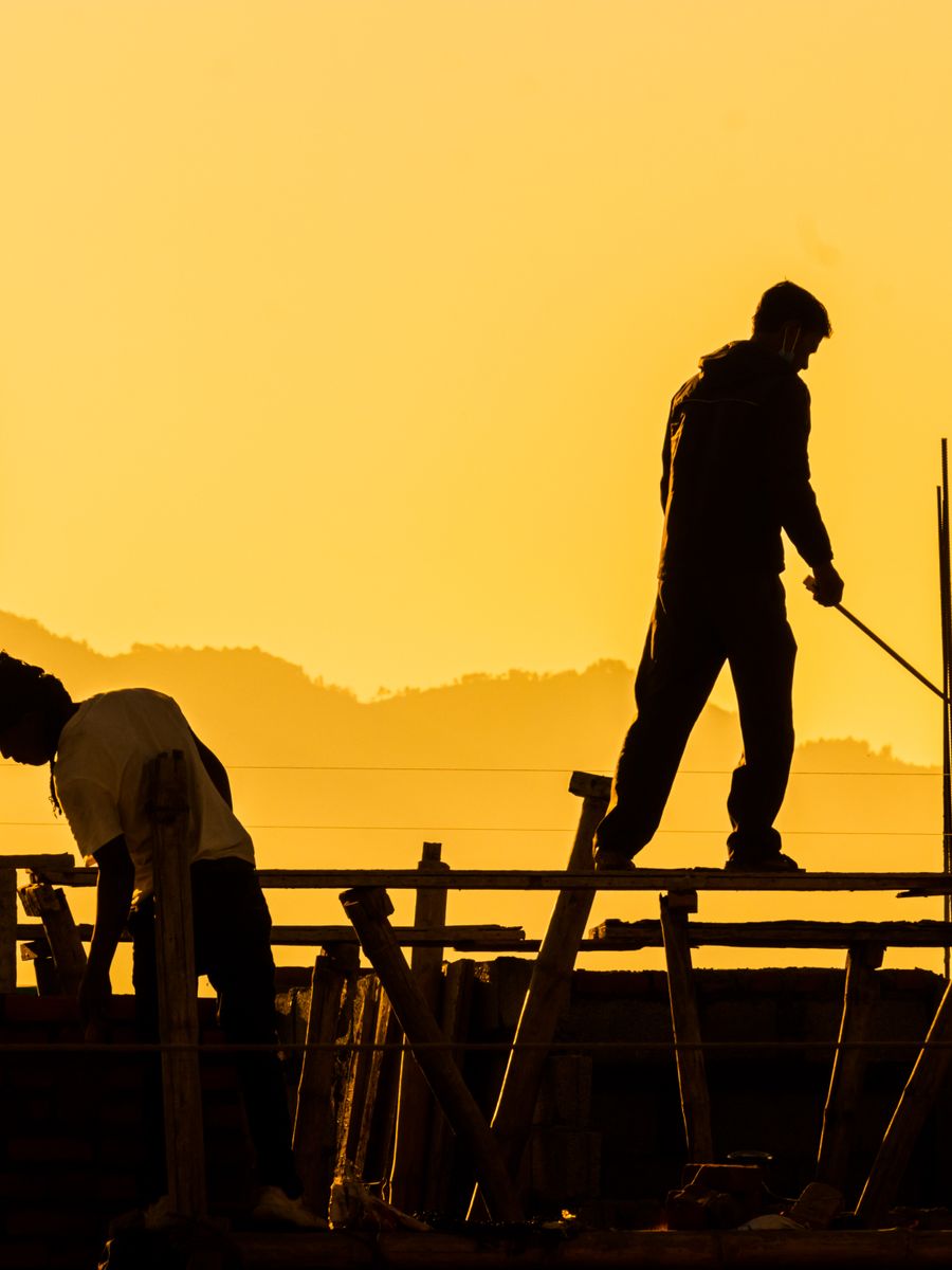 Construction workers silhouetted at sunset on a building site