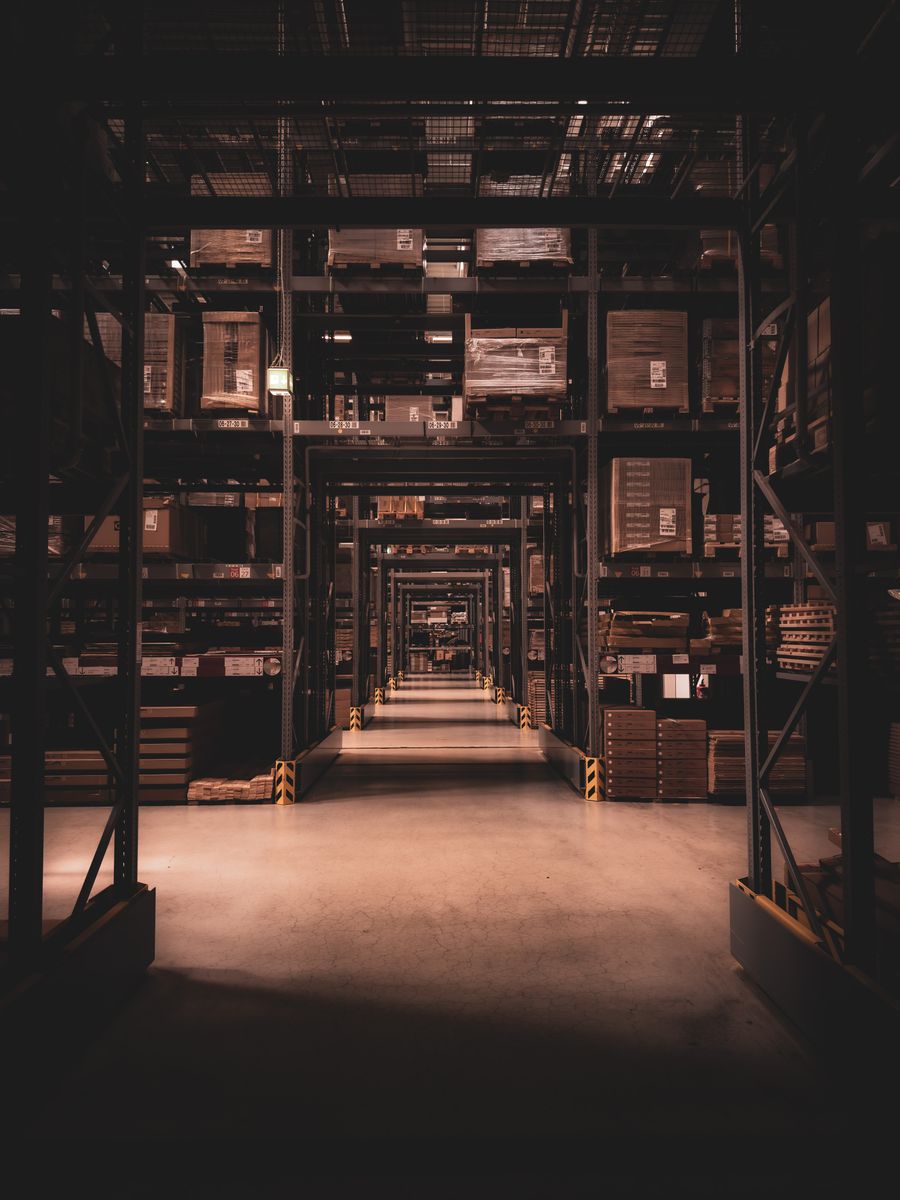 Dark warehouse corridor with shelves of inventory